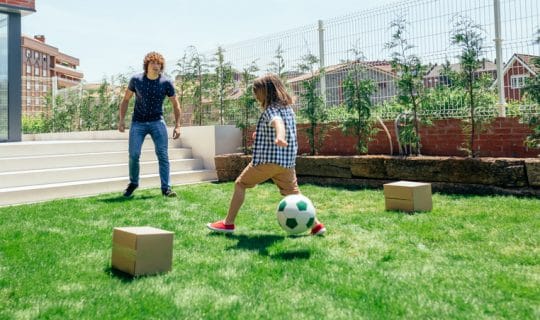Father and son playing soccer in the garden