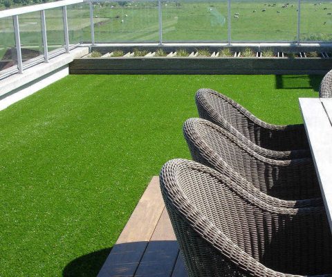 vibrant fake grass laid on balcony with view of farm land
