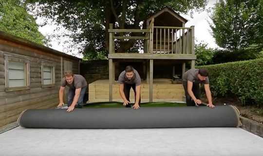 3 men roll out the fake grass ontop of sub base