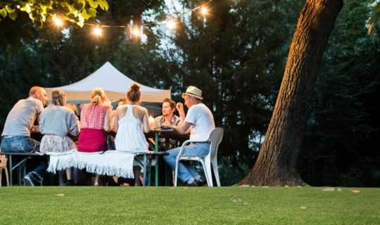family dining on fake grass under fairylights