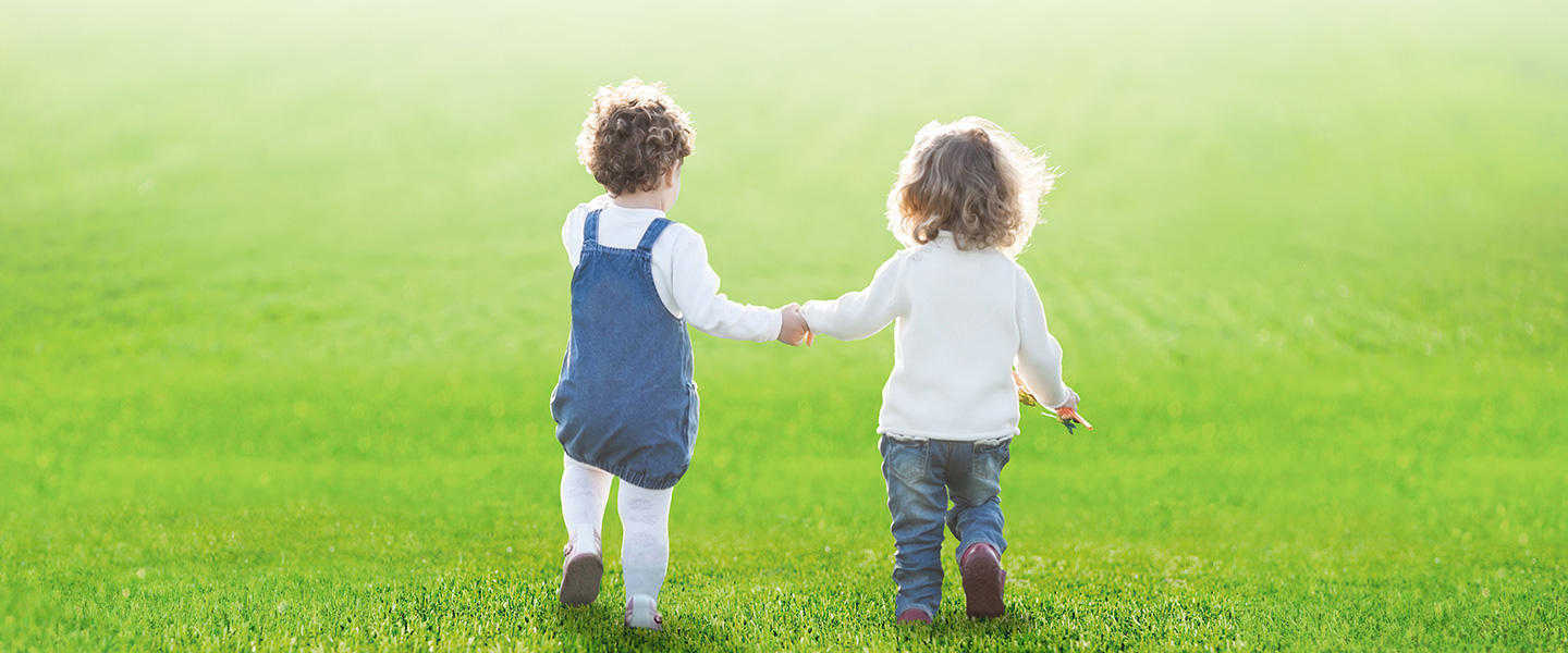 Children holding hands playing on fake grass