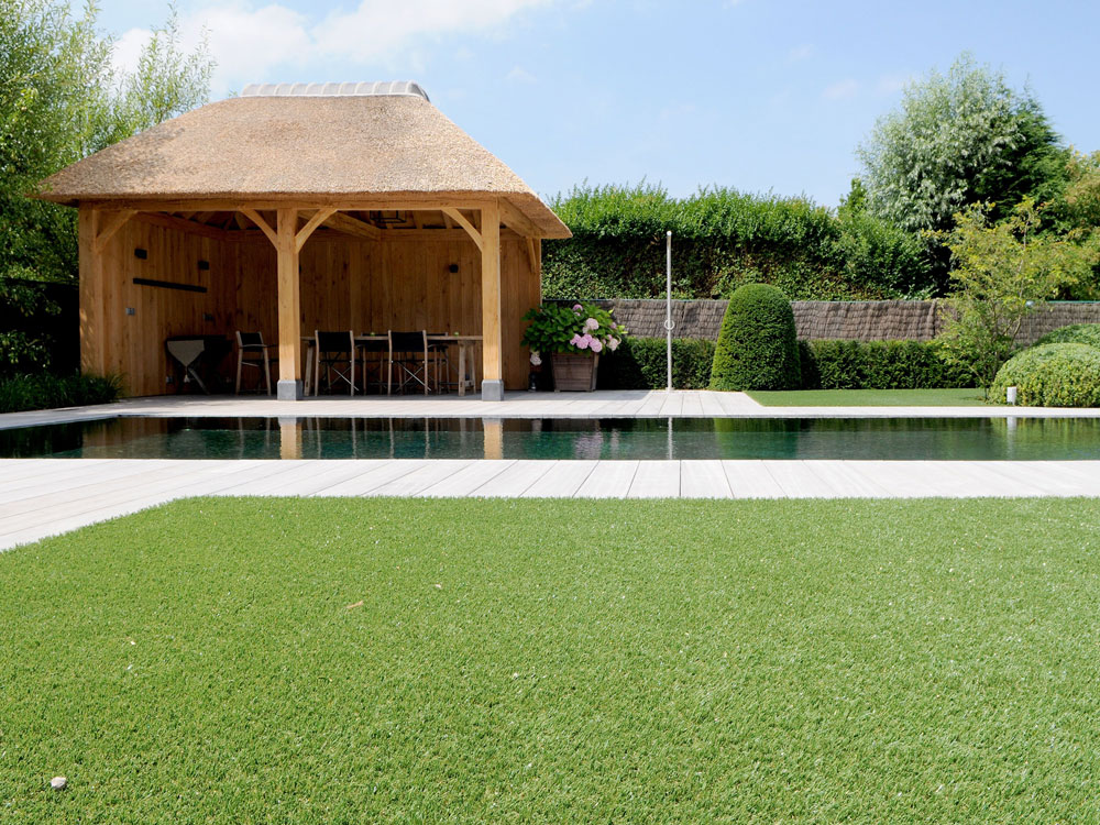 A pool with and pool house next to fake grass